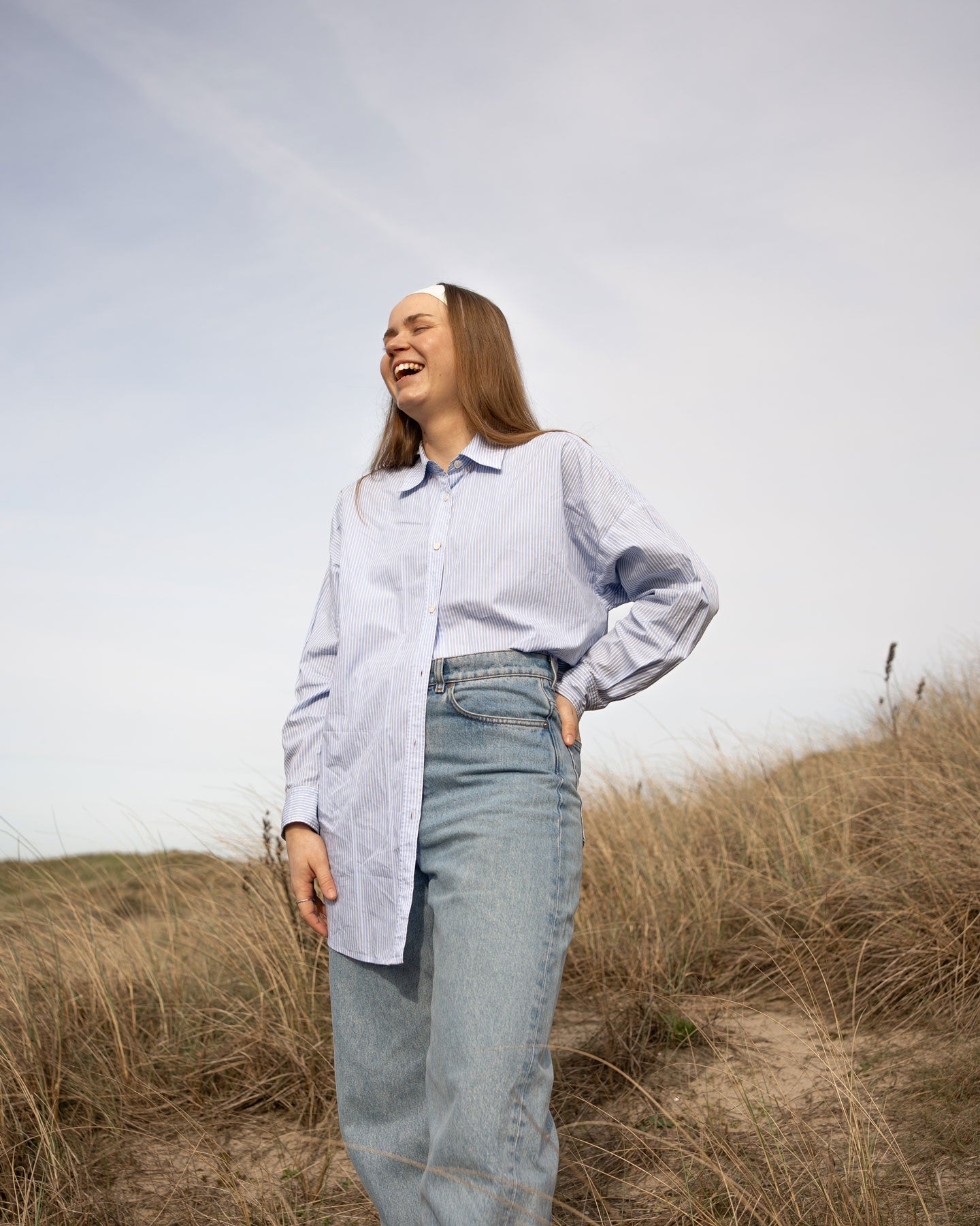 Model laughing in dunes with headband